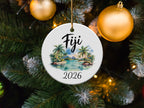 Round ornament with a tropical beach scene and "Fiji 2026" text.