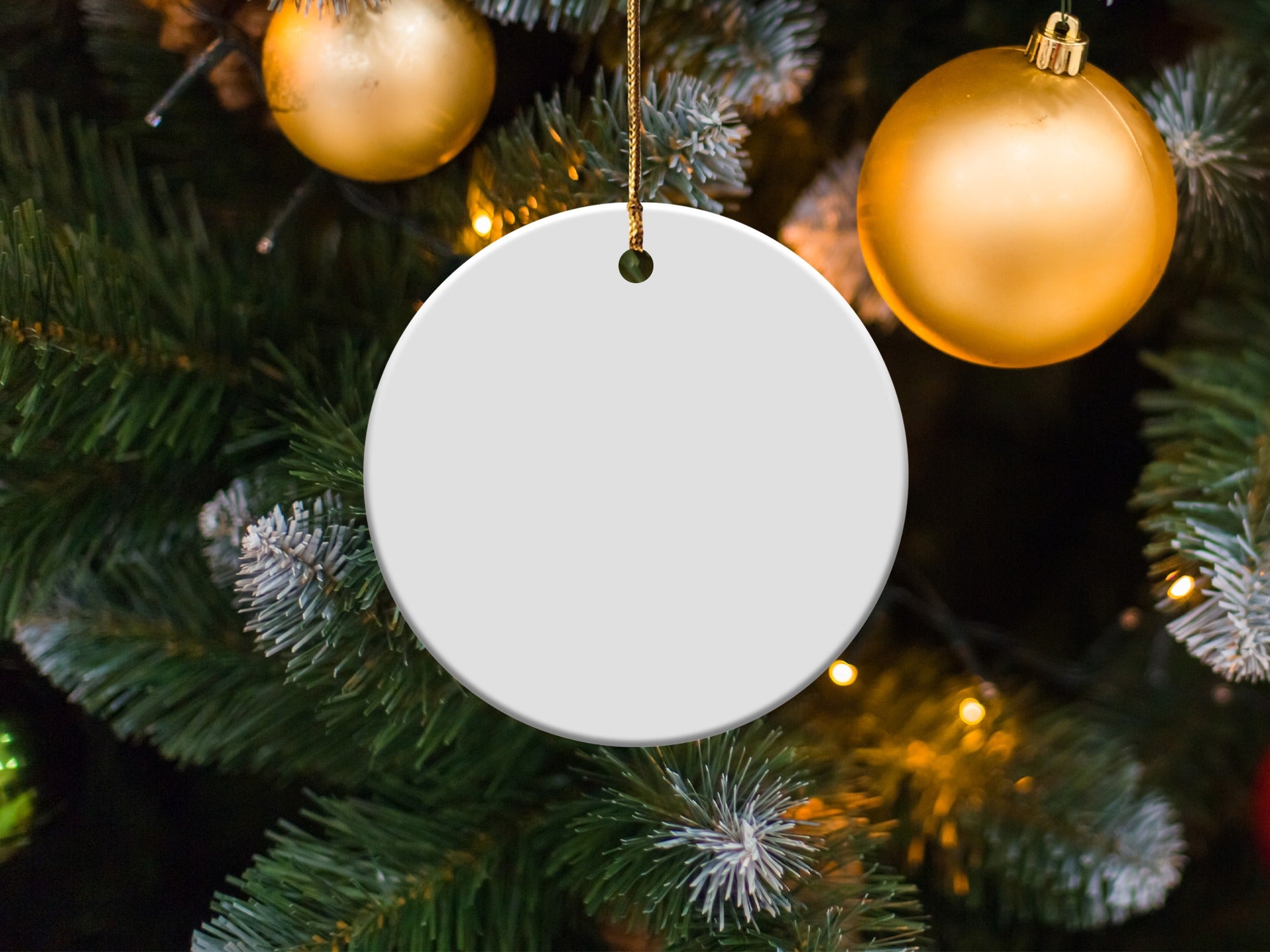 Blank white round ornament on Christmas tree with golden ornaments.