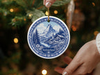 Round ornament with blue and white Swiss mountain village scene and "Switzerland" text.