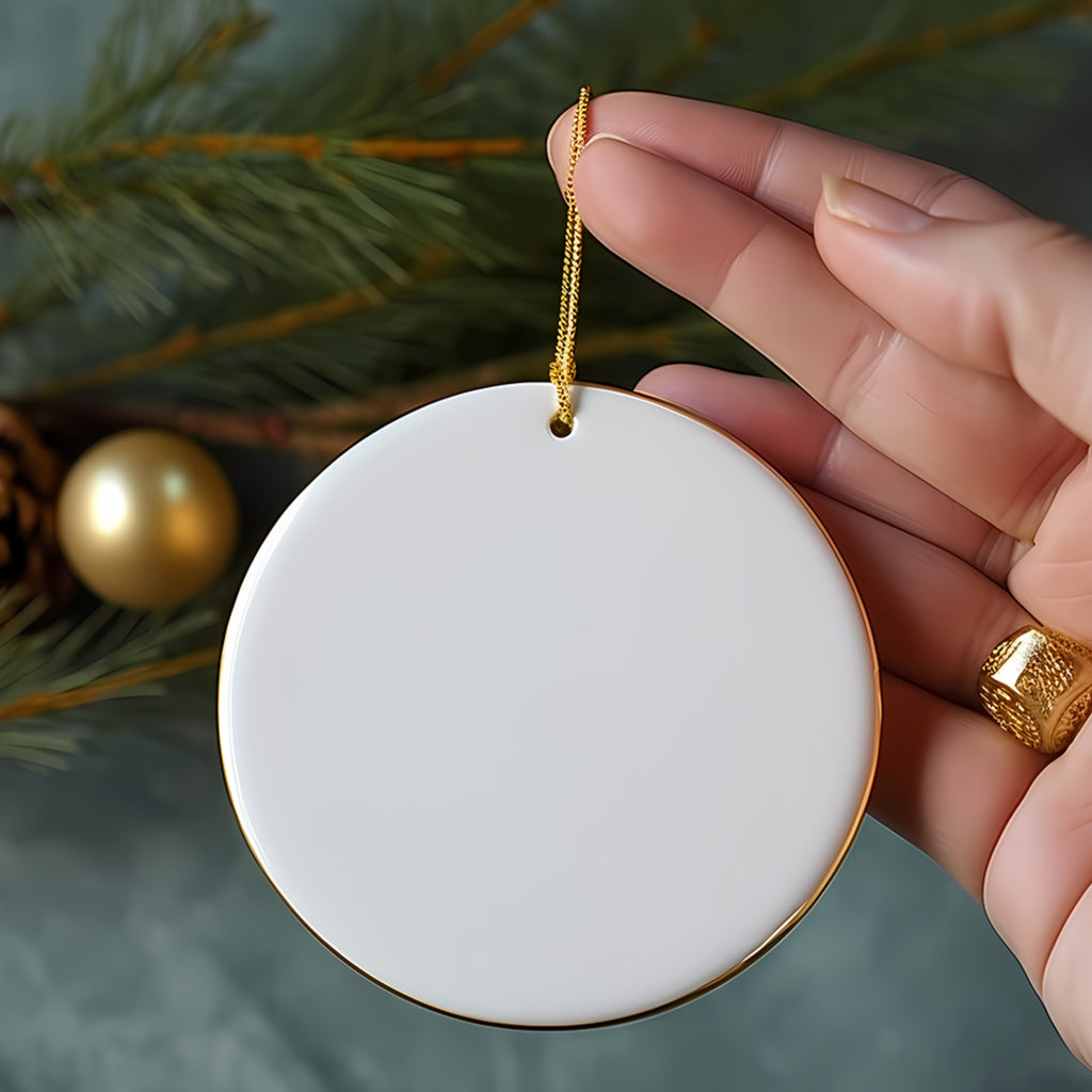 Blank white ceramic round ornament with gold trim held in hand.