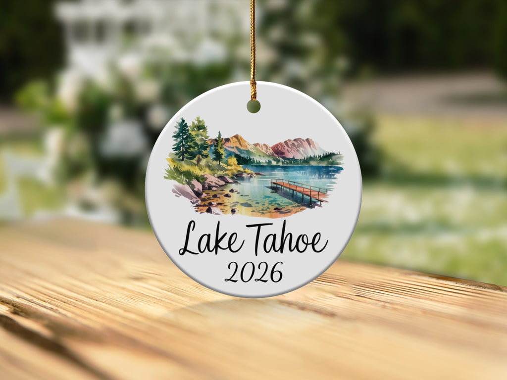 Ceramic ornament with watercolor Lake Tahoe scene and "Lake Tahoe 2026" text.