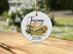 Round ceramic ornament with Tuscan landscape and "2026" text.