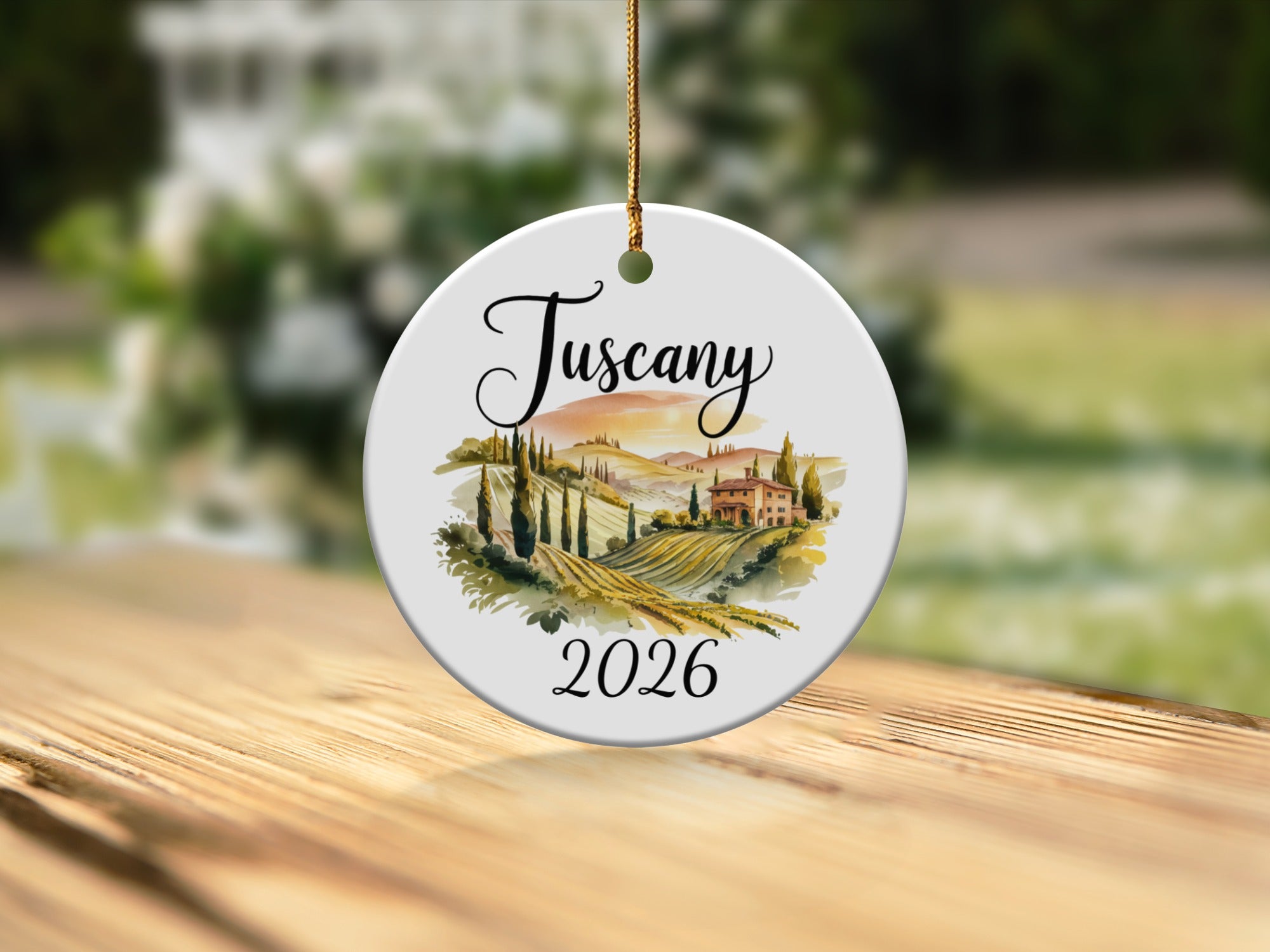 Round ceramic ornament with Tuscan landscape and "2026" text.