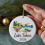 White ceramic ornament featuring a watercolor scene of Lake Tahoe with text.