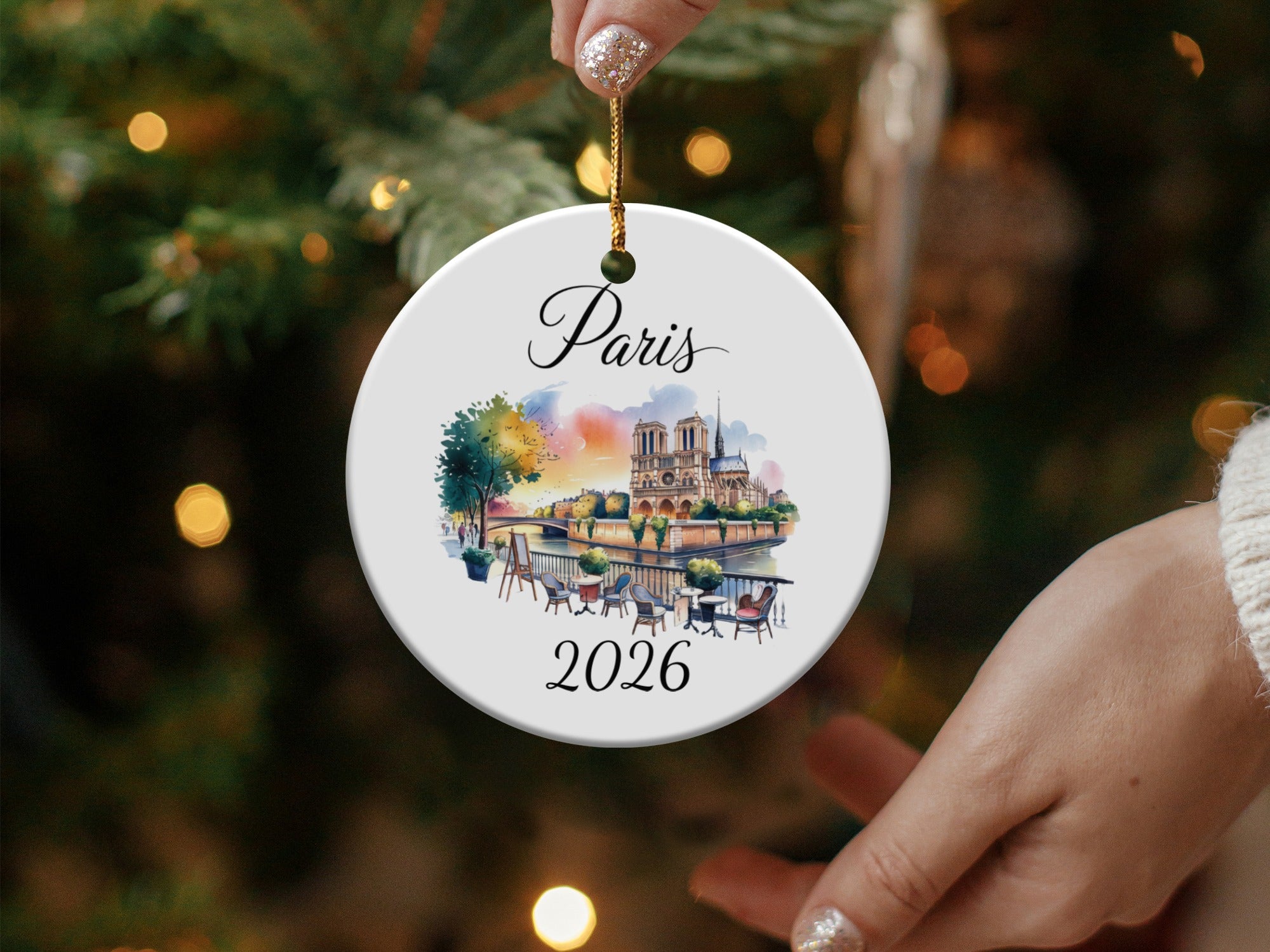 Round ornament depicting Notre Dame Cathedral and Parisian bridge, with "Paris 2026" text.