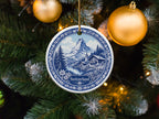Round ornament with a blue and white Swiss mountain village scene, text "Switzerland".