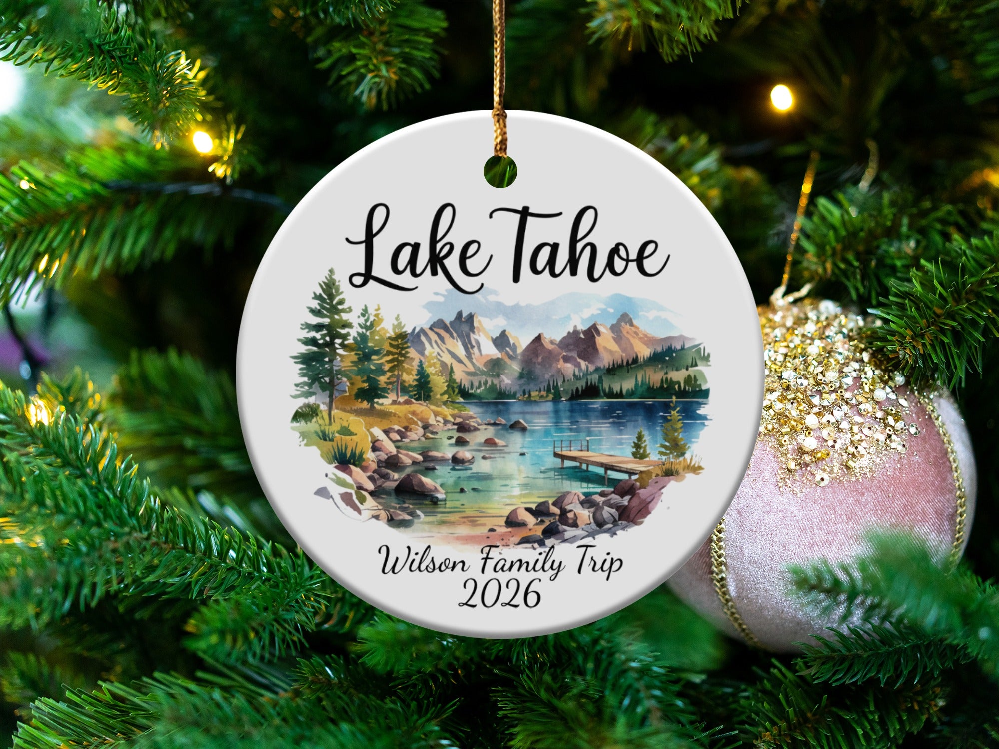 Round ornament with "Lake Tahoe" and "Wilson Family Trip 2026" text, featuring a scenic lake and mountains.