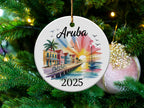 Round ornament featuring "Aruba 2025" and a watercolor scene with buildings and a sailboat.