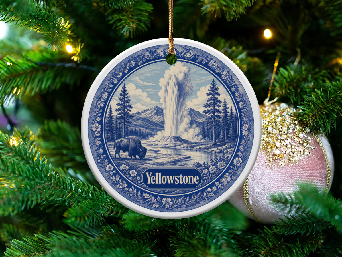 Round Yellowstone ornament with a bison and geyser scene, hanging on a Christmas tree.