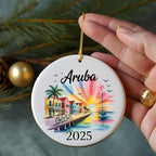 Aruba 2025 ornament with beach houses, palm trees, sailboat, and sunset.