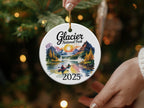 Round ceramic ornament with Glacier National Park scene, two kayakers, mountains, and the year 2025.
