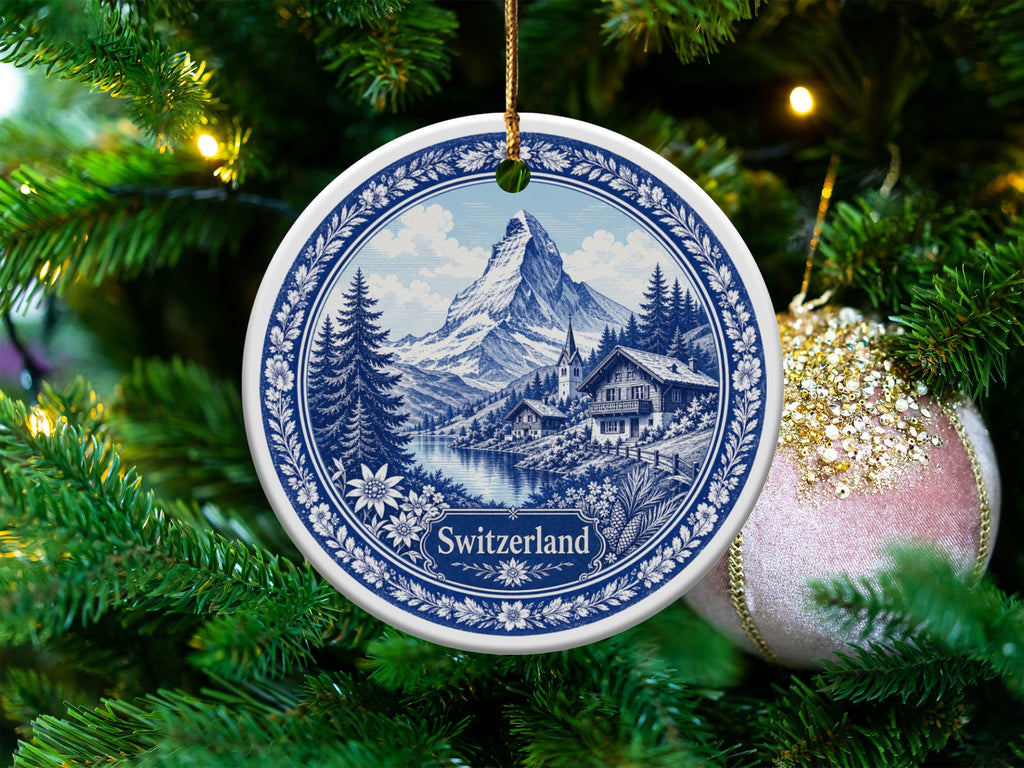 Blue and white ceramic ornament featuring a Swiss mountain village scene and the word "Switzerland".