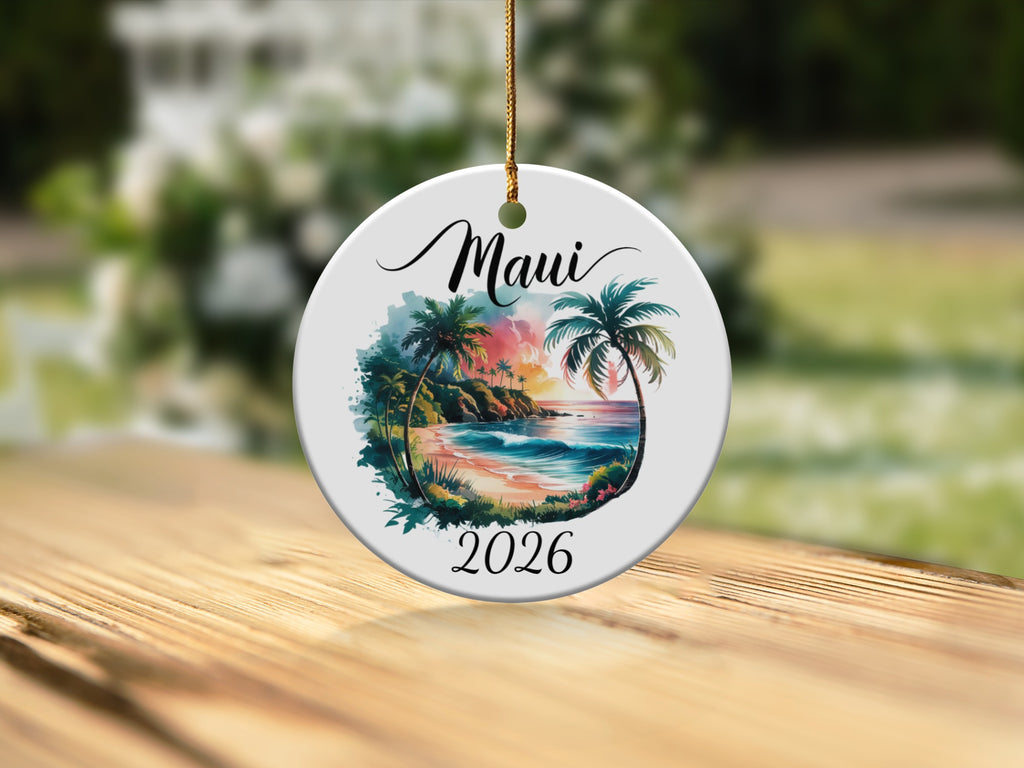 Round ceramic ornament depicting a tropical Maui beach scene with palm trees and the year 2026.