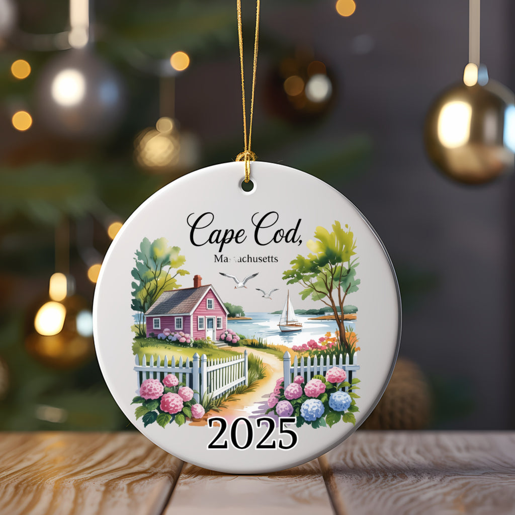 Ceramic ornament with Cape Cod 2025 scene: house, fence, water, and sailboats.