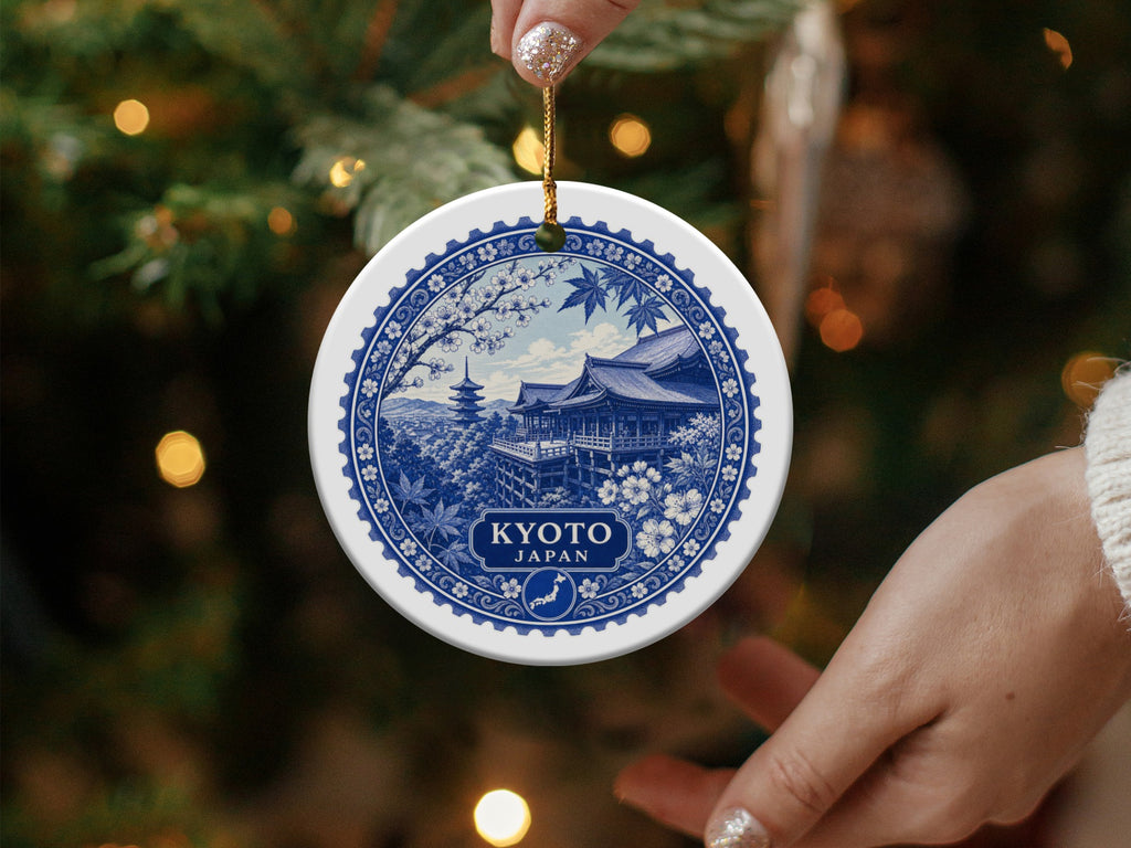 Round ceramic ornament with blue and white Kyoto, Japan scene, held near a Christmas tree.