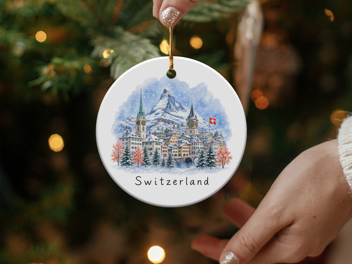 Round ceramic ornament with watercolor painting of a Swiss village and text "Switzerland".