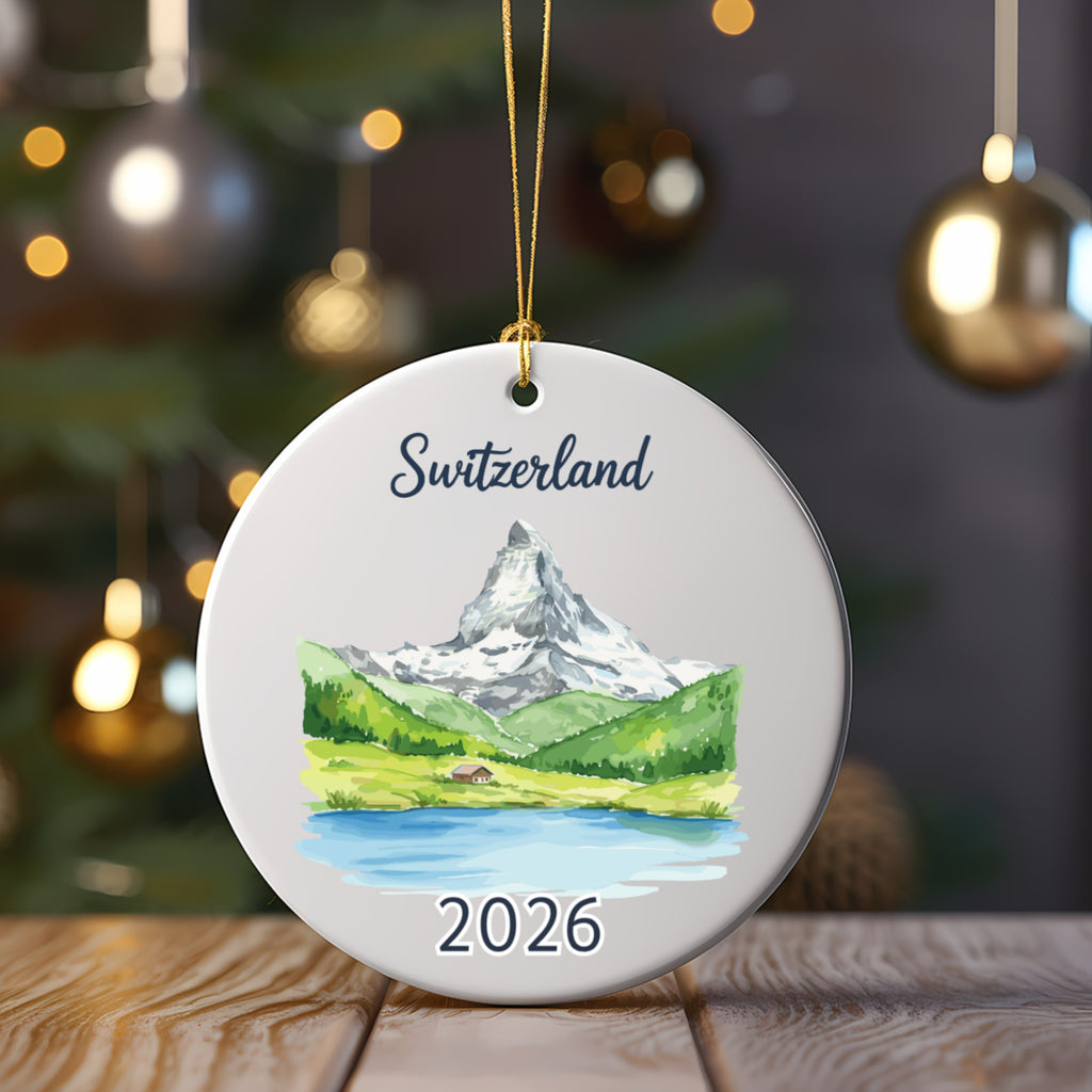 Round ornament with watercolor scene of Matterhorn, lake, and "Switzerland 2026" text.