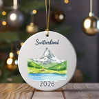 Round ornament with watercolor scene of Matterhorn, lake, and "Switzerland 2026" text.
