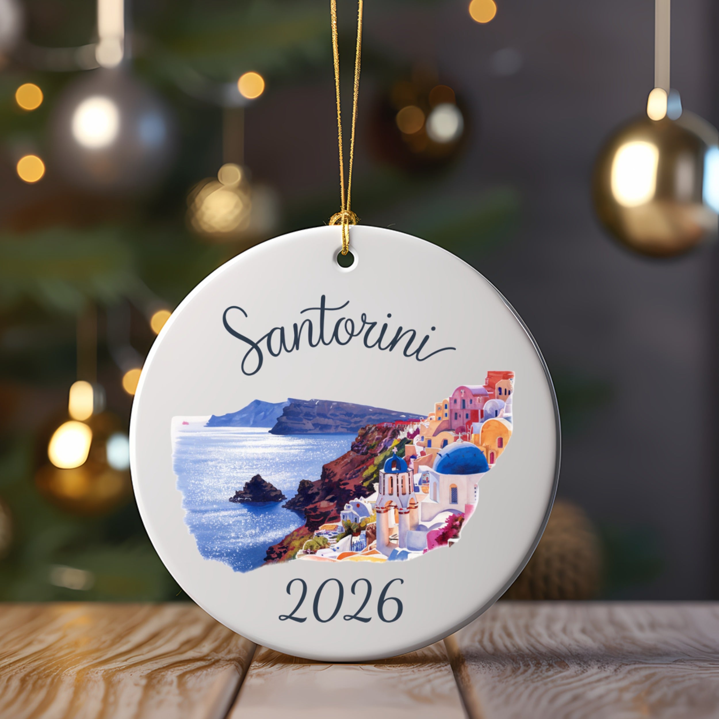 White round ornament with "Santorini 2026" and colorful buildings on a cliffside.