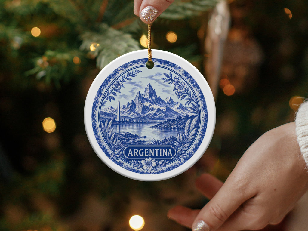Round ceramic ornament with blue and white scene of mountains, city, and lake, labeled "ARGENTINA."