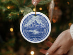 Round ceramic ornament with blue and white scene of mountains, city, and lake, labeled "ARGENTINA."