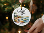 Round ornament with "Caramel by the Sea" and "2025" above a coastal scene.
