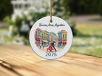 Round ornament with watercolor painting of Buenos Aires tango dancers in front of colorful buildings, dated 2026.