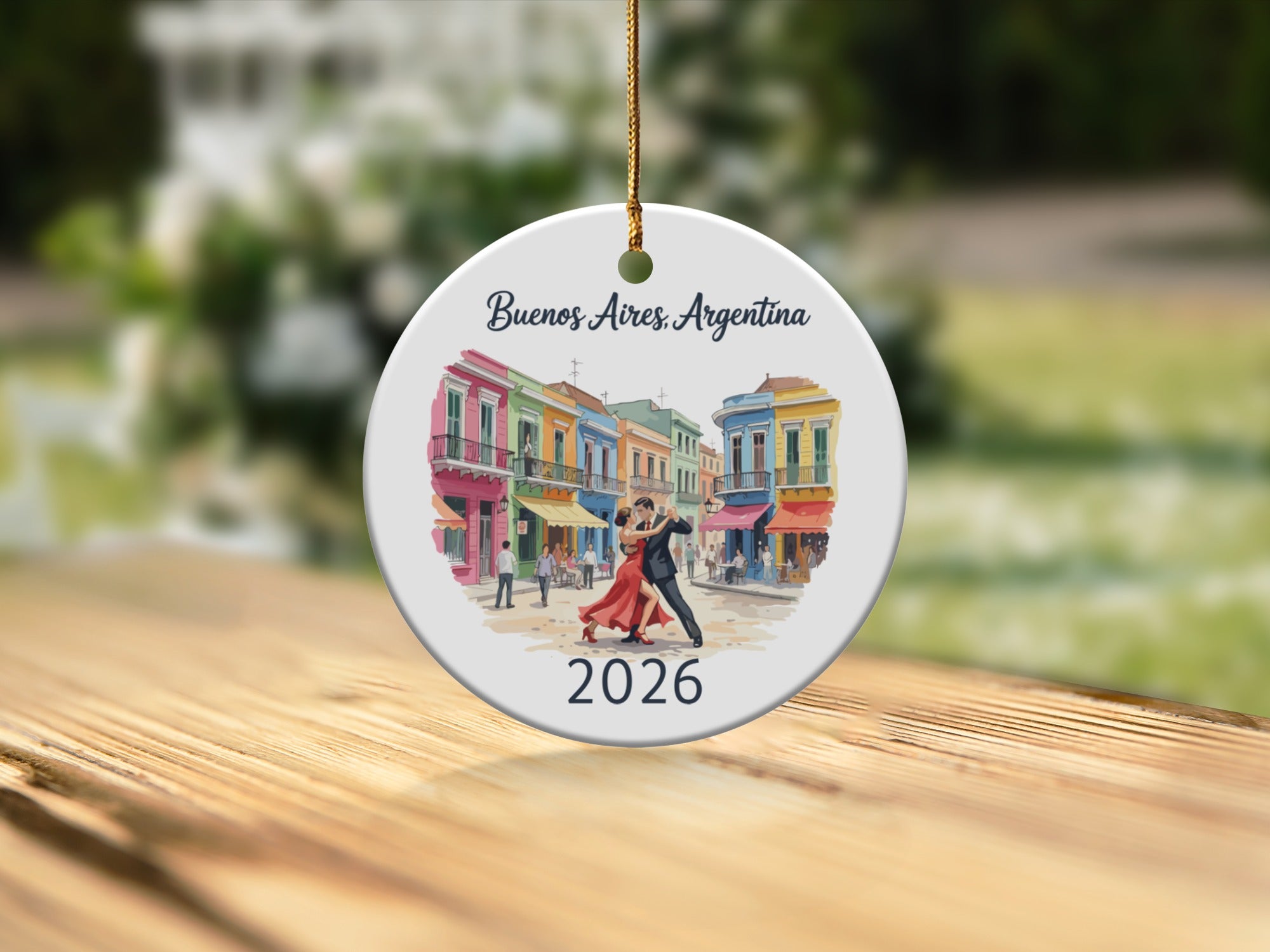 Round ornament with watercolor painting of Buenos Aires tango dancers in front of colorful buildings, dated 2026.