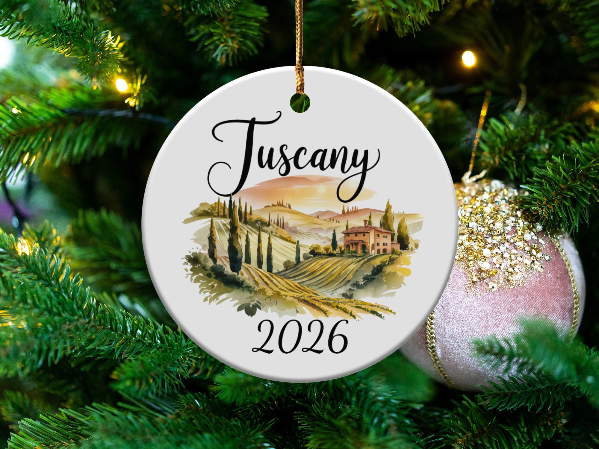 Round ornament with "Tuscany 2026" text and scenic vineyard landscape.