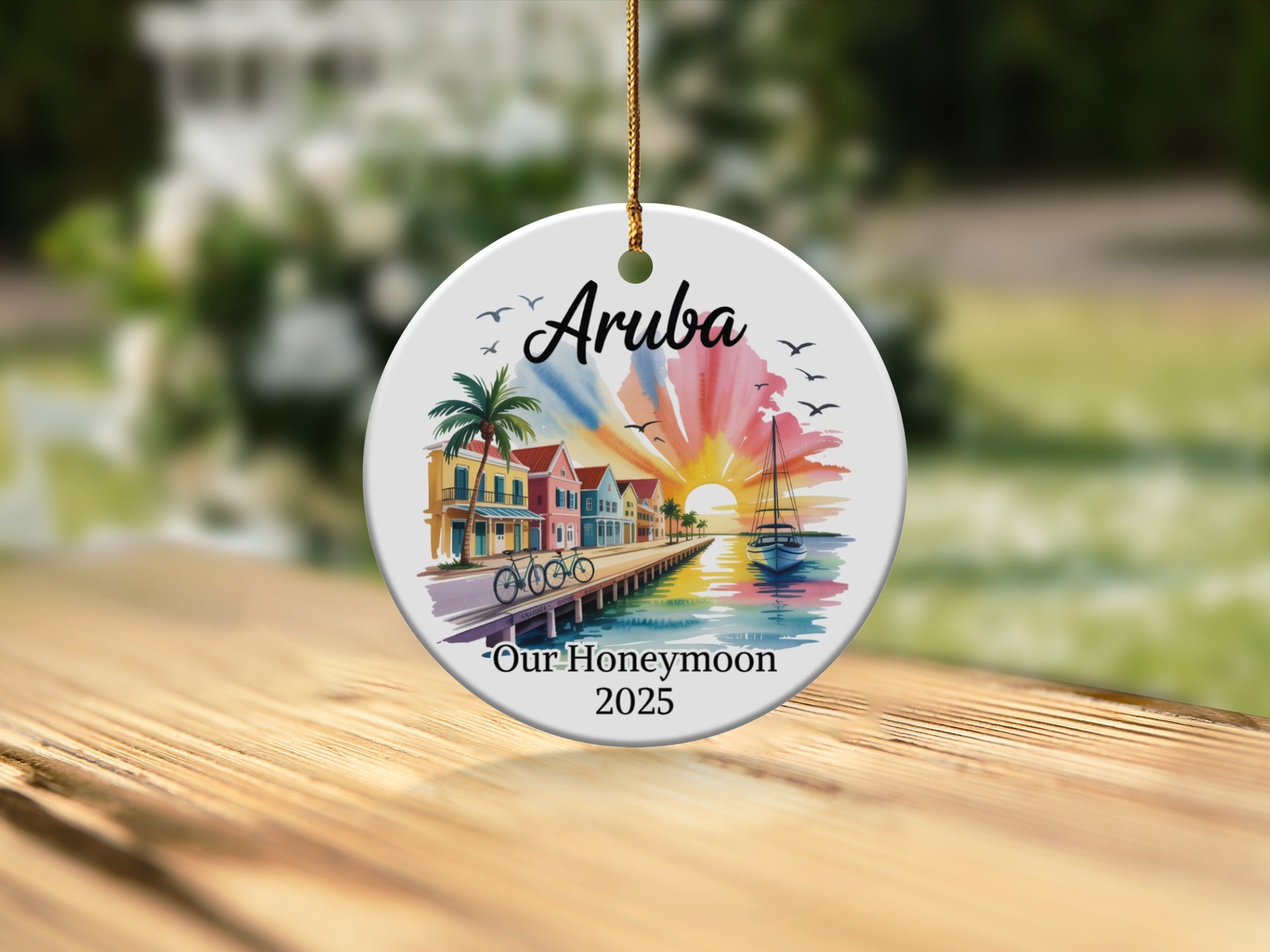 Round ceramic ornament with "Aruba Our Honeymoon 2025" and colorful beachfront scene.