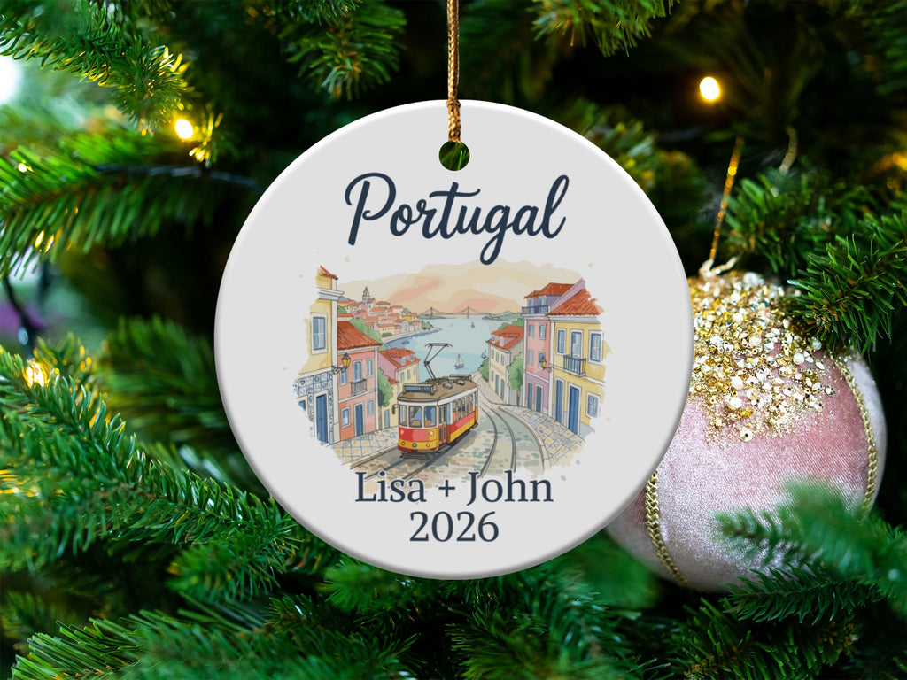 Round Christmas ornament with Portugal scene and personalized text "Lisa + John 2026".