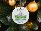 Round ornament with Matterhorn mountain scene and "Switzerland 2026" text.
