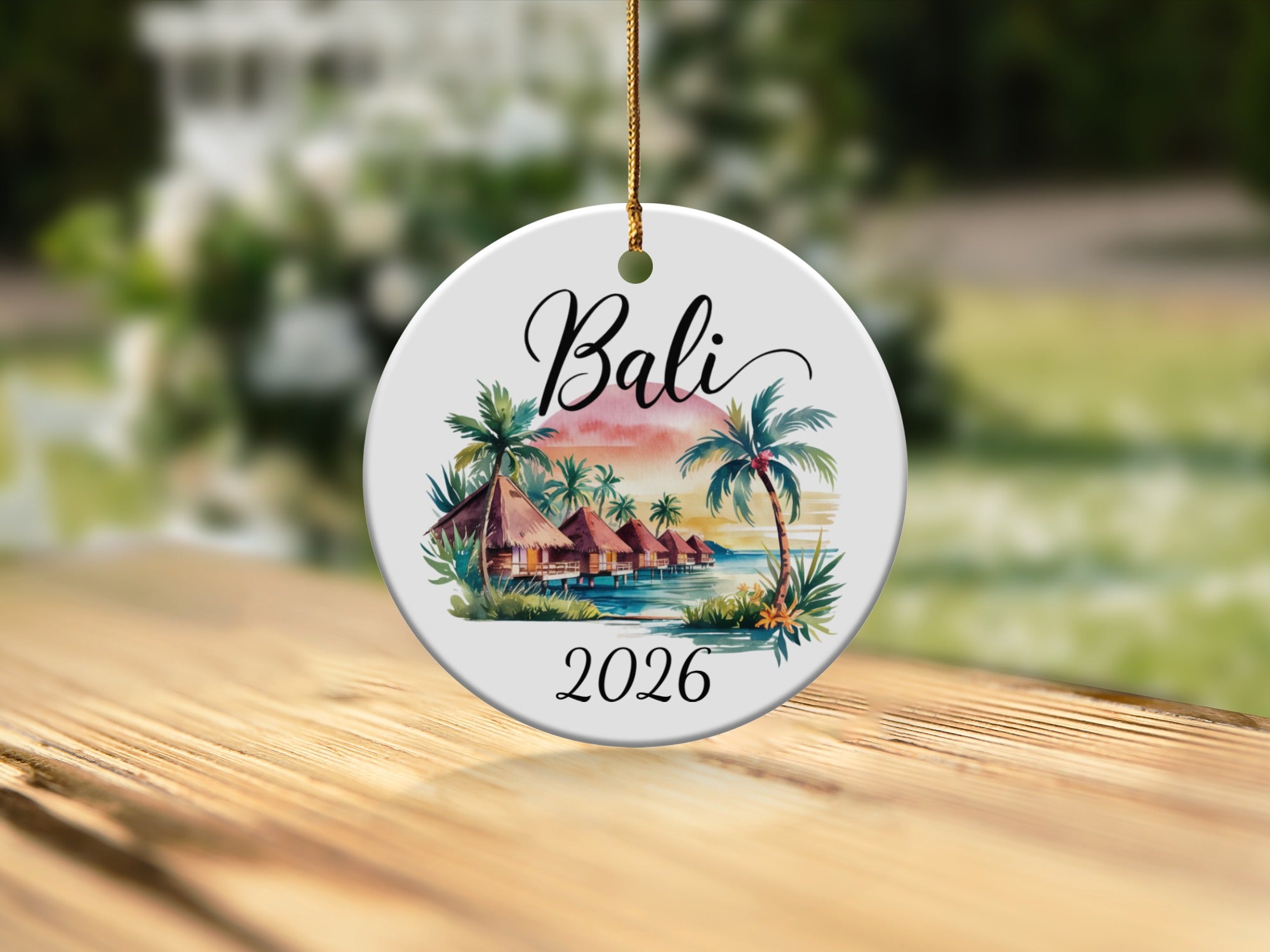 Round ceramic ornament with tropical huts, palm trees, and "Bali 2026" text.