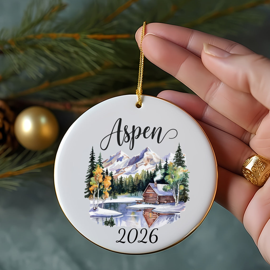 Round Aspen ornament with log cabin scene, mountains, and 2026.