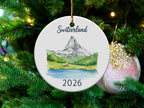 Round Christmas ornament with Matterhorn mountain scene and "Switzerland 2026" text.