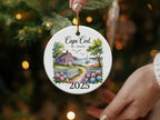 Cape Cod Massachusetts 2025 ceramic ornament with a house, fence, and sailboat.